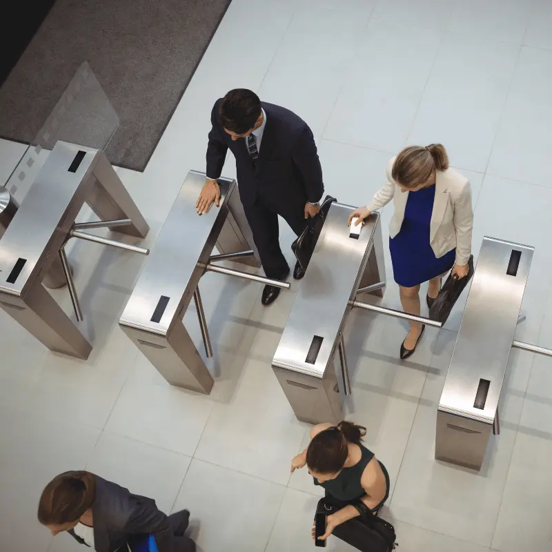 professionals scanning keycards to pass through tripod turnstiles in a lobby