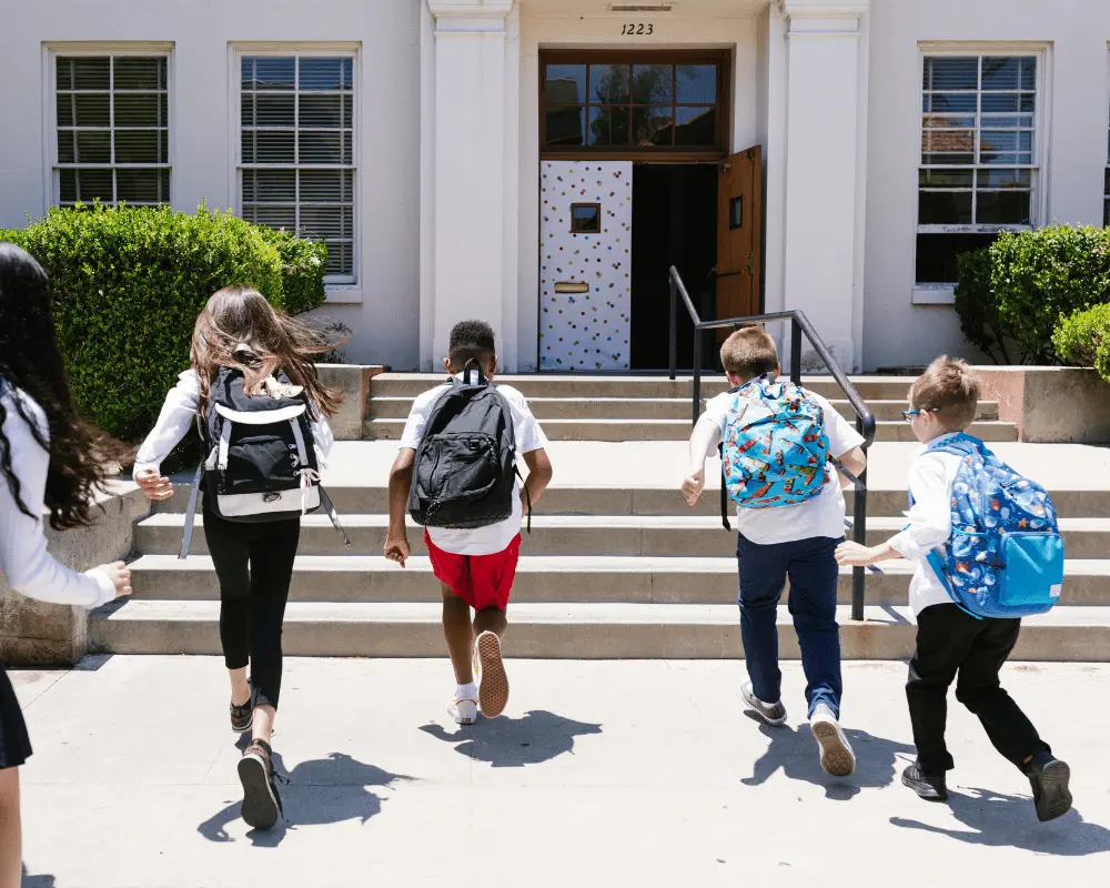 Grade-school students running towards the entrance of a school