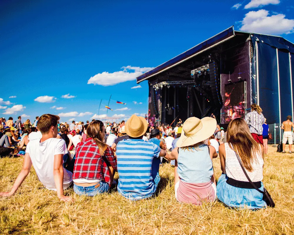 Concert attendees sitting outside in front of a stage