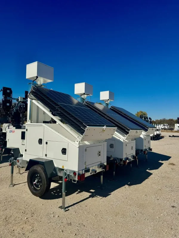 Three solar-powered security trailers lined up in a row in an outdoor parking lot